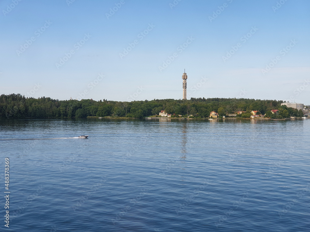 A boat on the sea outside Stockholm Sweden with green forest and TV tower Kaknästornet visible in the distance