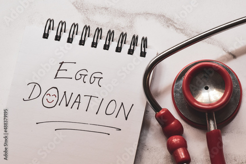 Egg donation handwritten text with smiley face on notepad with stethoscope. In-vitro fertilization, artificial insemination, surrogacy concept. photo