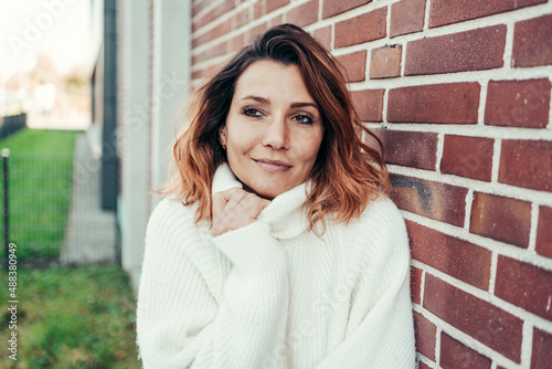 Canvas Print Dreamy young woman snuggling into a warm turtleneck sweater