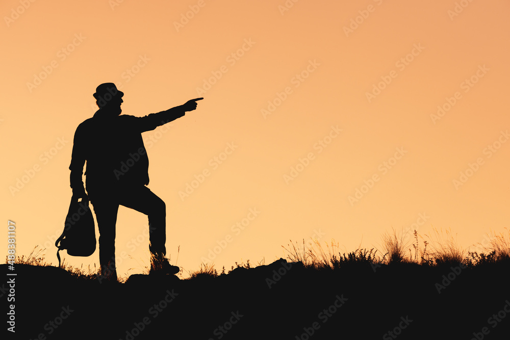 silhouette of man in hat on orange background with bag in his hand silhouette of man in hat on orange background with bag in his hand