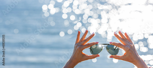 Schilderij op canvas Sonnenbrille in einer Frauenhand vor unscharfen Hintergrund mit Bokeh Reflexen