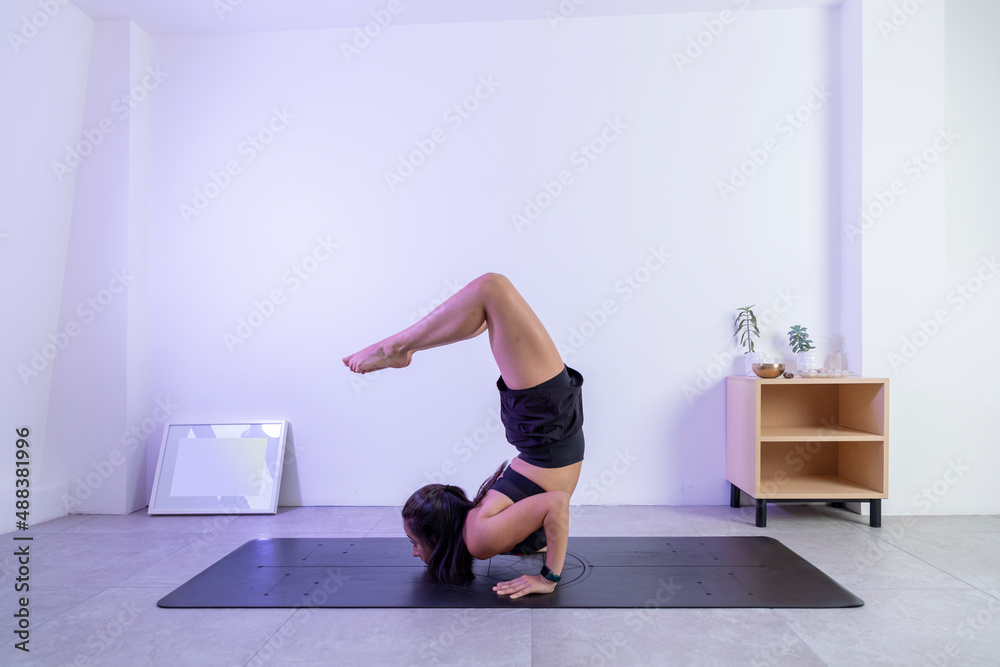 Posing process, of a woman doing the scorpion pose in a yoga studio, wearing sportswear