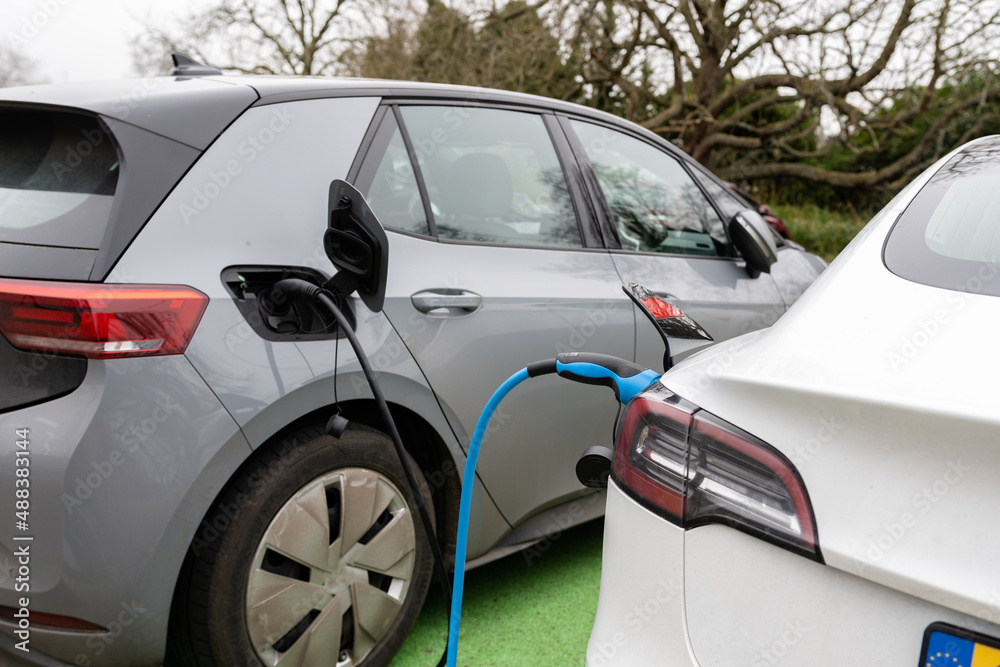 Electric cars charging at plug in charge station in a public car park in Suffolk, UK