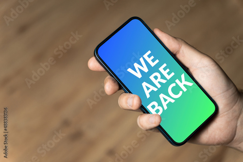 We are back - hand holding a phone