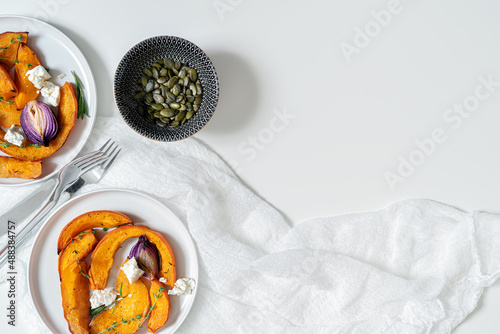 Roasted pumpkin,onion, garlic , thyme, rosemary and pampkin seeds on white background. Rustic food photography.  Close-up. Top view with copy space.