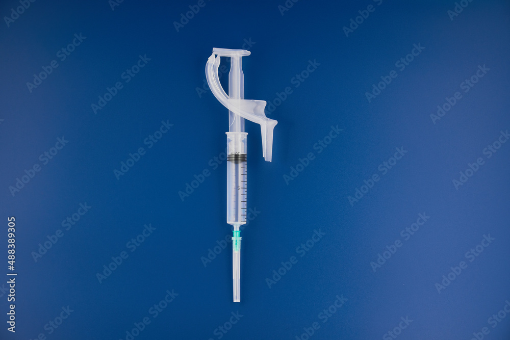Syringe with needle lies on blue background Syringe with needle lies on blue background