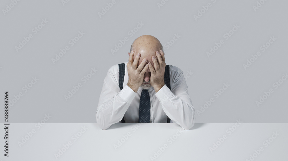 Frustrated desperate businessman with head in hands