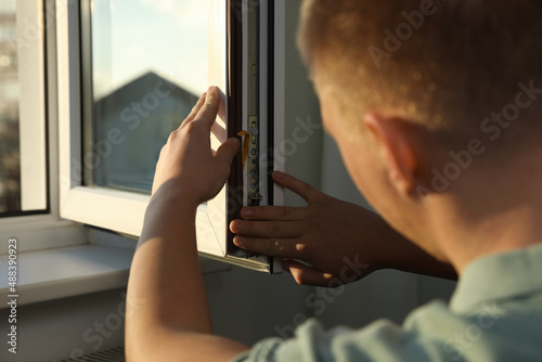 Construction worker putting sealing foam tape on window indoors, closeup