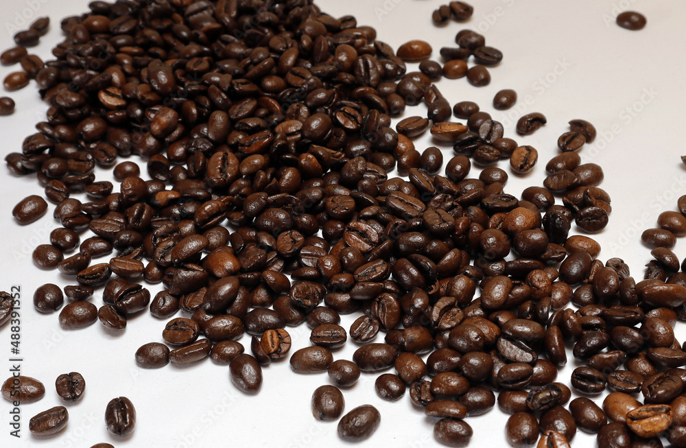 Naklejka premium Coffee beans on a white background, close-up with free space, horizontal, selective focus.