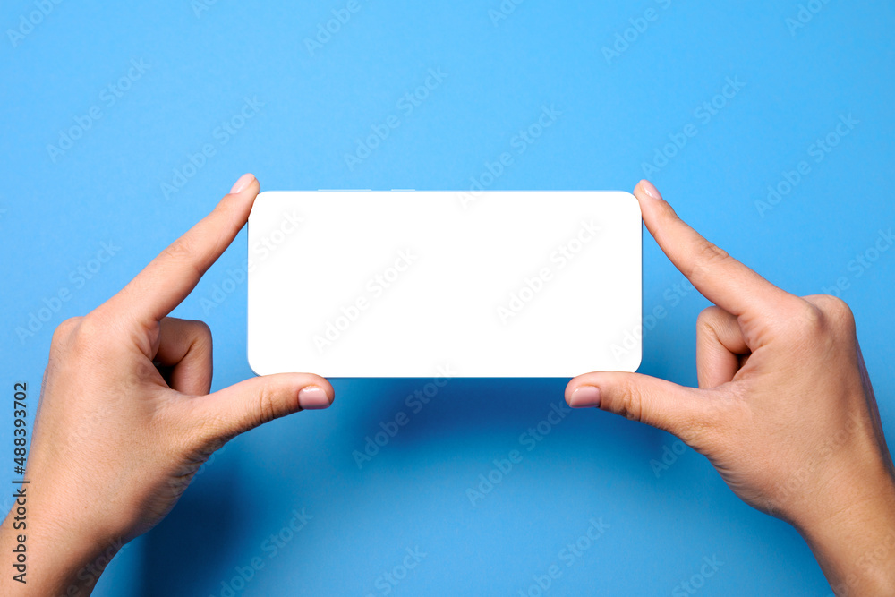 mobile phone with white blank empty screen in hands over blue background, layout image mobile phone with white blank empty screen in hands over blue background, layout image