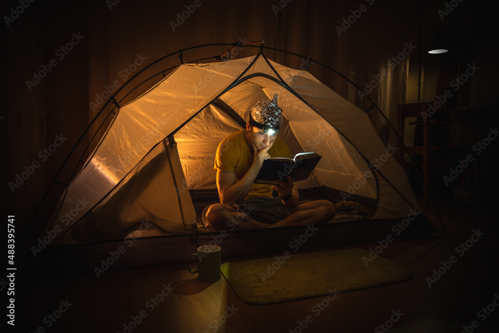 Man sitting in a tent wearing a tinfoil hat - obrazy, fototapety, plakaty 