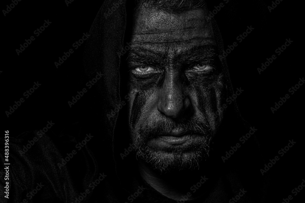 Viking man with a furious gaze and a painted face looks into the darkness with bright eyes Viking man with a furious gaze and a painted face looks into the darkness with bright eyes