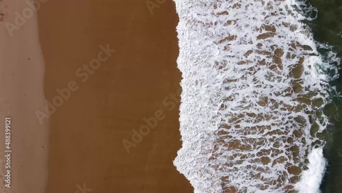 Aerial drone view of sea waves crashing in the beach sand. Costa vicentina, Portugal.