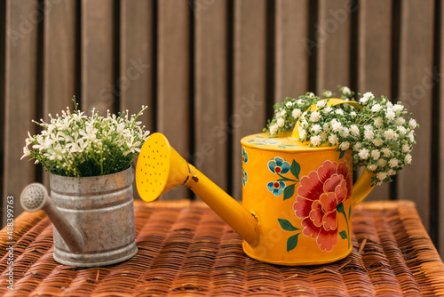 White flowers in yellow and silver vases on wood table 
