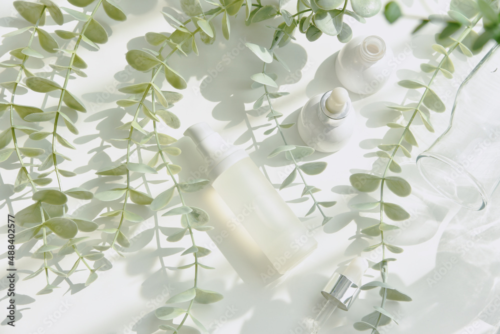 Cosmetic bottle containers packaging with green herbal leaves in shadow and light effect, Blank label for organic branding mock-up, Natural skincare beauty product concept.