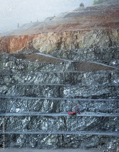 Red drilling machine on a bench of diabase quarry in misty morning photo