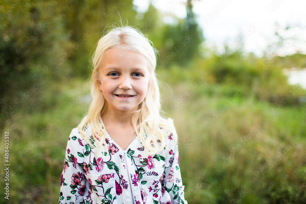Stunning young blonde girl wearing flower dress outside.