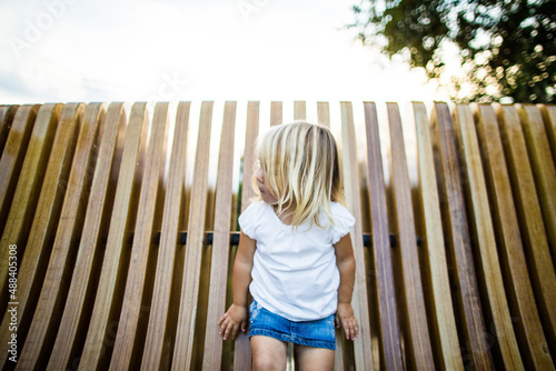 Portrait of young blonde girl girl playing on a bench. photo