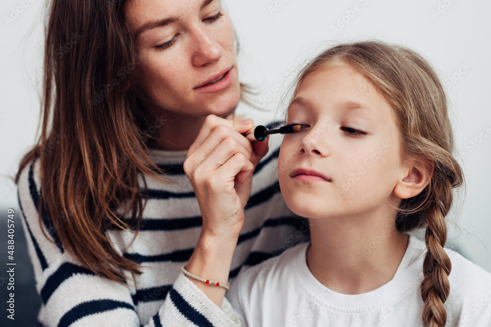 Mother puts mascara on her daughters eyelashes Mother puts mascara on her daughters eyelashes