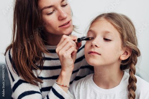 Mother puts mascara on her daughters eyelashes