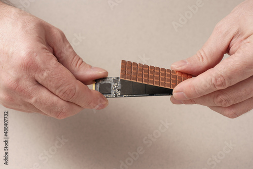 Men's hands hold SSD and install cooling radiator. photo