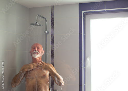 Senior man taking a shower in the bathroom in the morning.