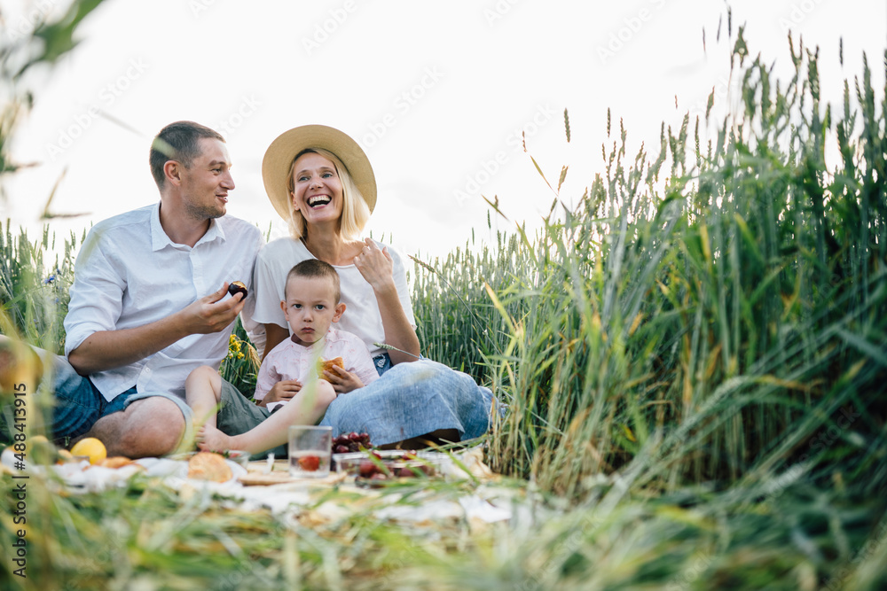 Happy family spending time together outside in nature on vacation outdoors. Mom, dad and son sitting on weat field at nature countryside. The concept of family holiday. Happy family spending time together outside in nature on vacation outdoors. Mom, dad and son sitting on weat field at nature countryside. The concept of family holiday.
