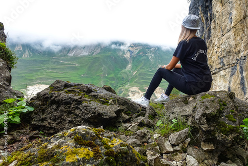 A girl on the background of a mountain landscape in the clouds. Stone bowl in Dagestan. Russia