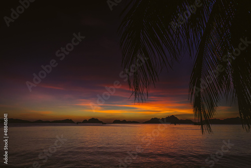 Picturesque tropical sunset. Dramatic evening sky above island. Palm tree and isles silhouettes. Exotic seascape in evening twilight. El Nido lagoon in night dusk. Tropical vacations. © Nataliia
