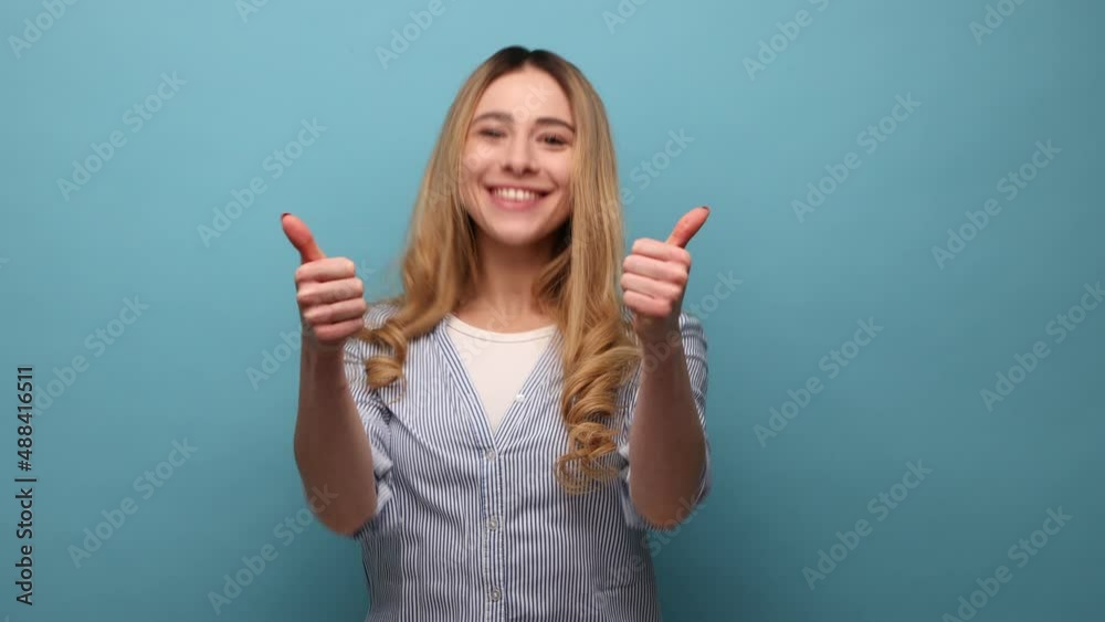 Well done, good job. Portrait of joyful woman showing thumbs up, like gesture to camera and smiling broadly, expressing approval, excellent feedback. Indoor studio shot isolated on blue background. Well done, good job. Portrait of joyful woman showing thumbs up, like gesture to camera and smiling broadly, expressing approval, excellent feedback. Indoor studio shot isolated on blue background.