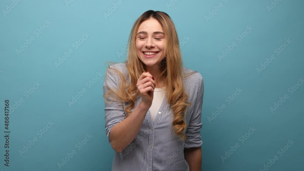 Shh, it's big secret. Beautiful cunning woman with wavy hair smiling, showing gesture secret sign with finger near her lips, wearing striped shirt. Indoor studio shot isolated on blue background. Shh, it's big secret. Beautiful cunning woman with wavy hair smiling, showing gesture secret sign with finger near her lips, wearing striped shirt. Indoor studio shot isolated on blue background.