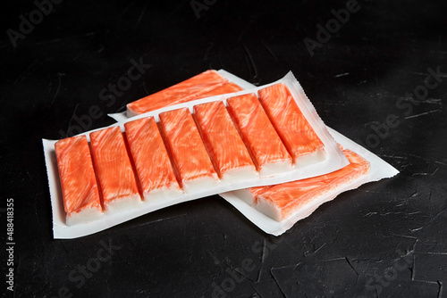 Photography Crab sticks or imitation crab meat on black table