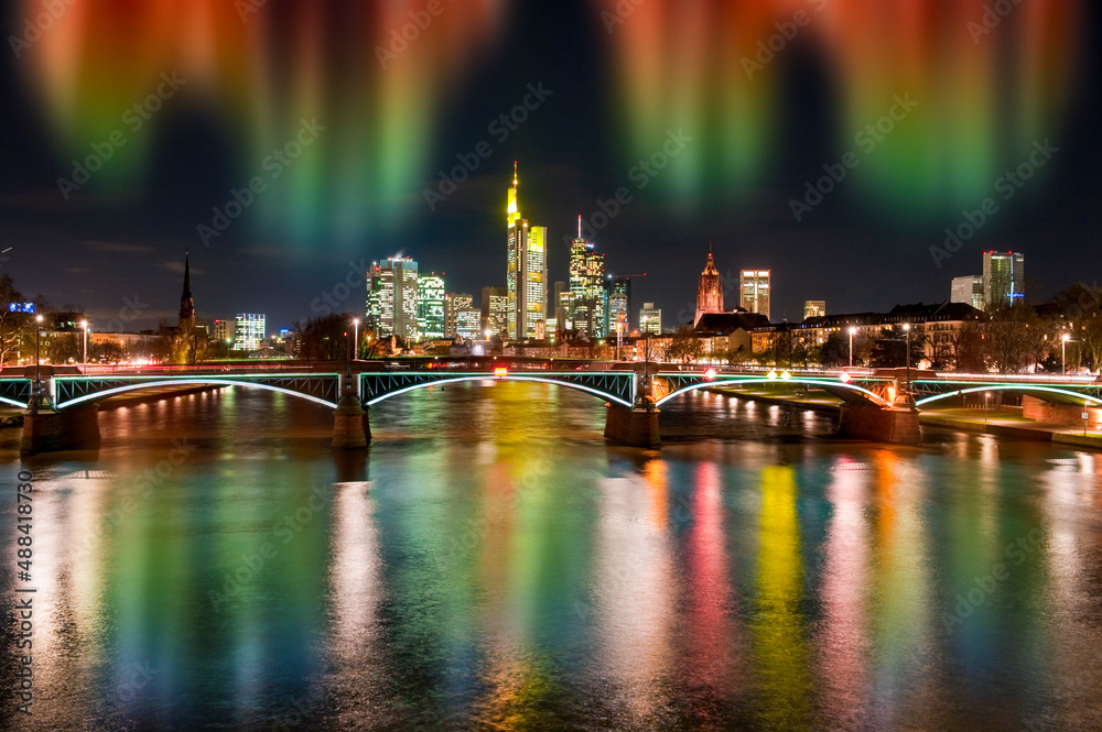Fototapeta premium Die Skyline von Frankfurt am Main am Abend mit Nordlichtern und Fluss im Vordergrund