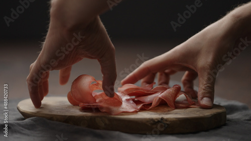 Tablou pe pânză man picking bresaola slices from olive cutting board