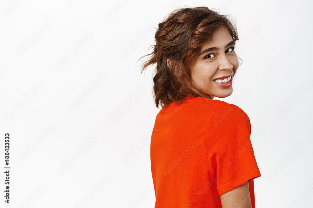 Portrait of attractive young hispanic woman with short curly hair, posing half turned, face looking at camera with cute feminine smile, standing in red tshirt over white background Portrait of attractive young hispanic woman with short curly hair, posing half turned, face looking at camera with cute feminine smile, standing in red tshirt over white background