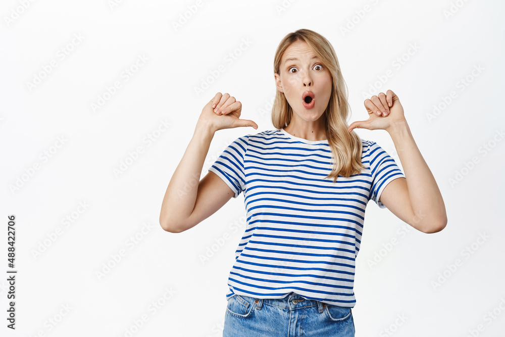 Enthusiastic beautiful woman pointing fingers at herself, self-promoting, talking about personal achievement, winning, feeling confident, white background Enthusiastic beautiful woman pointing fingers at herself, self-promoting, talking about personal achievement, winning, feeling confident, white background