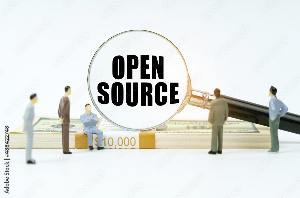 On a white surface, a dollar, figurines of people and a magnifying glass with the inscription - Open Source On a white surface, a dollar, figurines of people and a magnifying glass with the inscription - Open Source