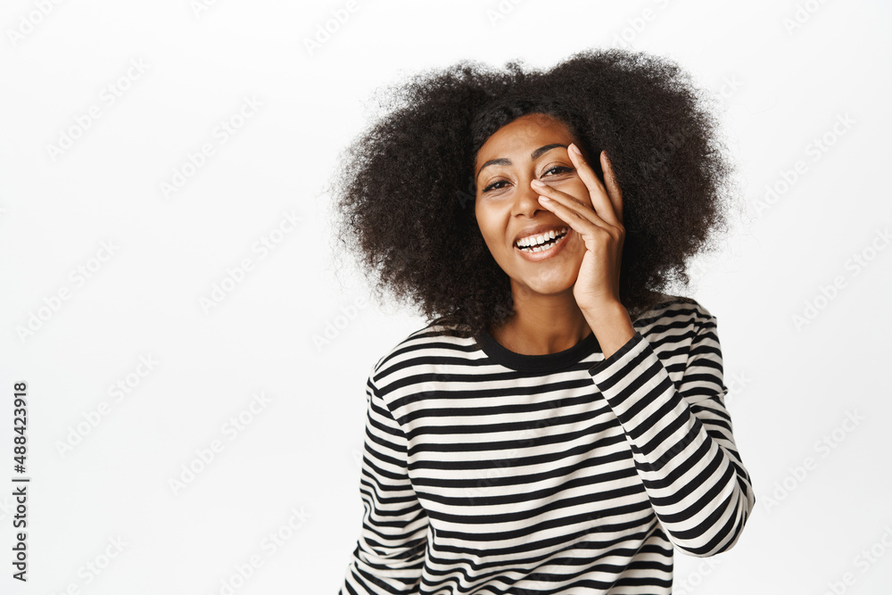 Beauty and skin care. Beautiful african woman 30 years old, touching her clear glowing young face, smiling and laughing, standing over white background Beauty and skin care. Beautiful african woman 30 years old, touching her clear glowing young face, smiling and laughing, standing over white background