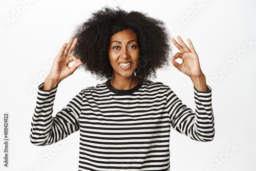 Okay, very good. Smiling african american female model, showing ok, zero gesture, praise smth, complimenting, recommending brad or store, white background