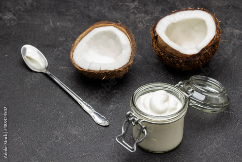 Two halves of coconut. Glass jar with coconut yogurt.