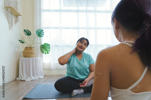 Fat Asian woman good mood sits and talks with a private yoga teacher. feels relaxed after practicing yoga, flexible body concept. 