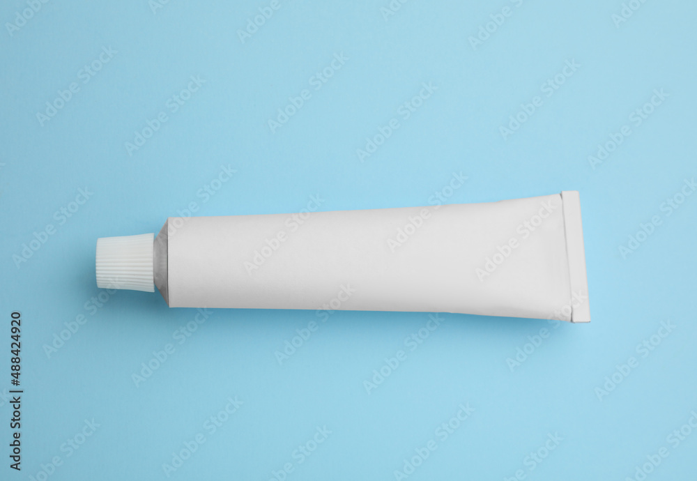 Blank white tube of ointment on light blue background, top view. Space for text - obrazy, fototapety, plakaty 