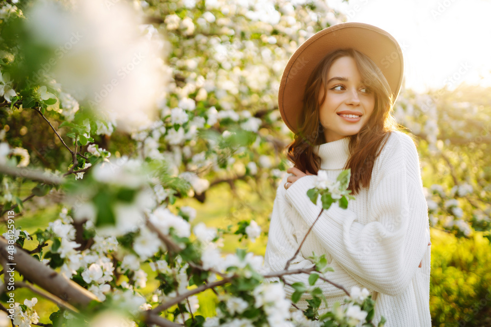 Young woman enjoying scent in blooming spring garden. The concept of relax, travel, freedom and spring vacation. Fashion style Young woman enjoying scent in blooming spring garden. The concept of relax, travel, freedom and spring vacation. Fashion style