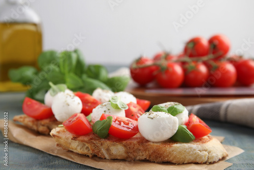 Delicious sandwiches with mozzarella, fresh tomatoes and basil on blue wooden table. Space for text