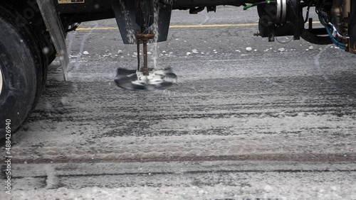 Truck mounted salter applying salt to snowy street. Toronto, Canada.