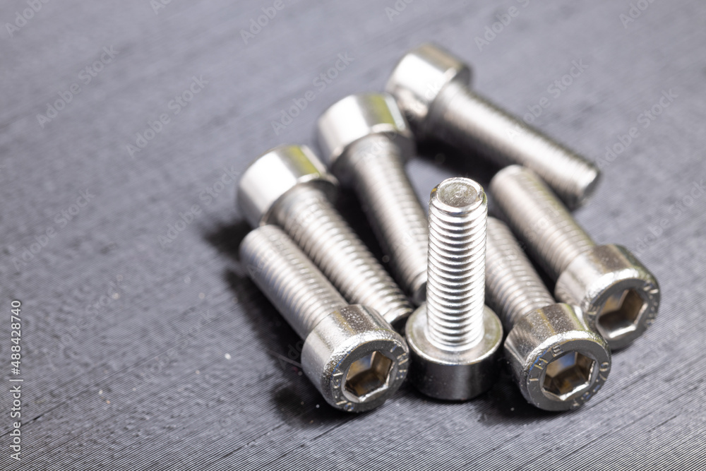 Fototapeta premium Chrome inbus nuts on the black background. Workshop concept with chrome nuts.