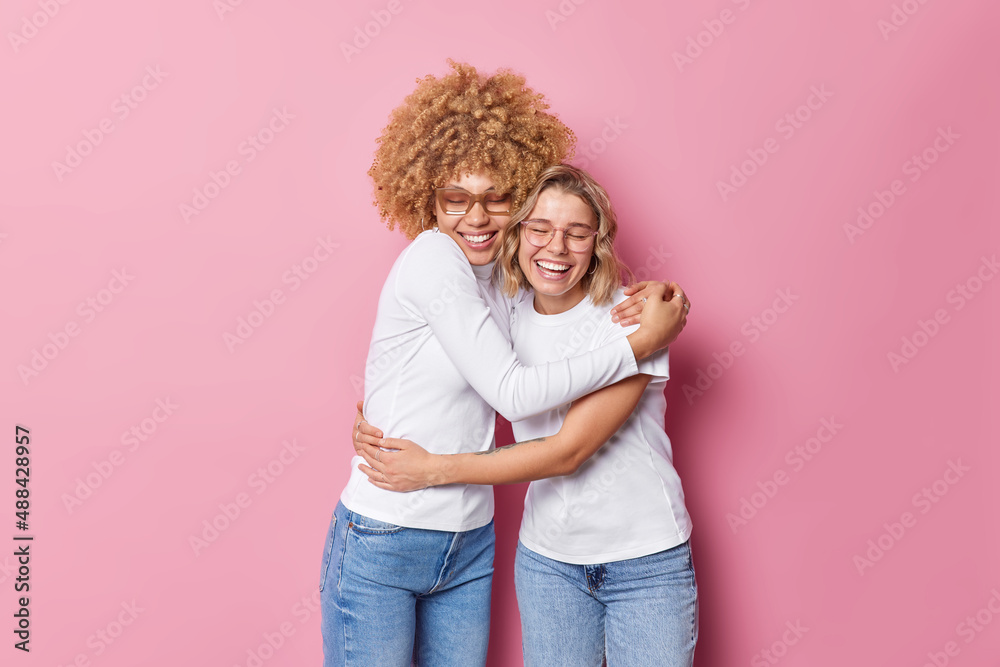 Friendly cheerful optimistic women embrace each other with love and smile gladfully have good relationship feel glad isolated over pink background. Friends spend family day together. Bonding concept - obrazy, fototapety, plakaty 