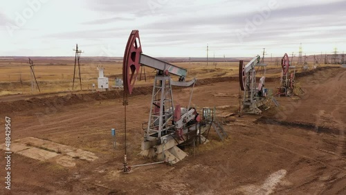 Pump jack in vast oil fields in Russia. Pipelines transporting oil from oil pumps, aerial drone shot