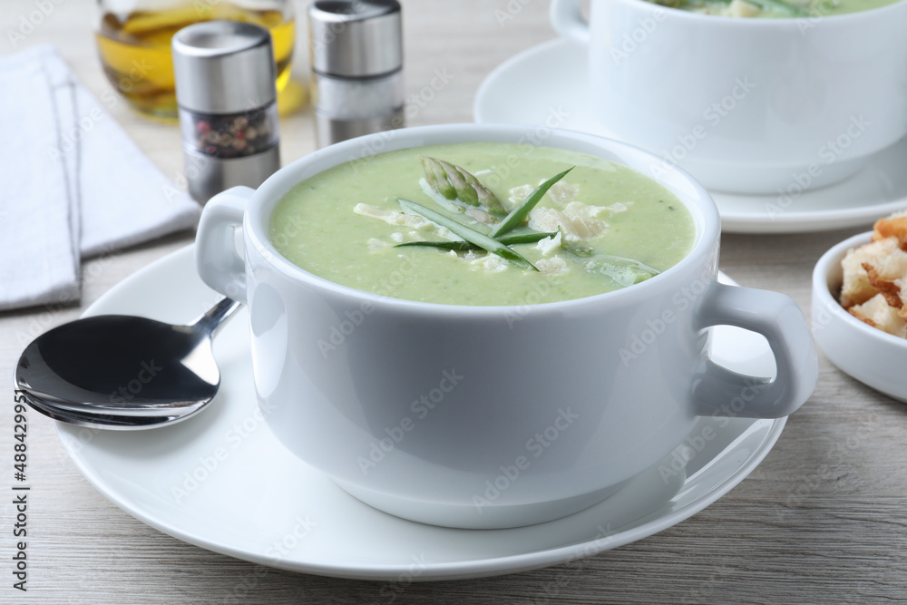 Delicious asparagus soup with green onion served on white wooden table, closeup Delicious asparagus soup with green onion served on white wooden table, closeup