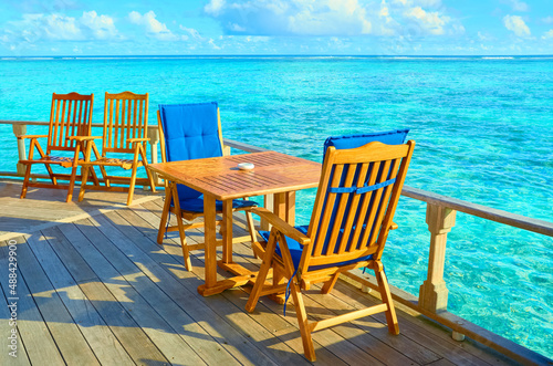 Tables with chairs on the shore of the azure ocean. © Lexis_Jan